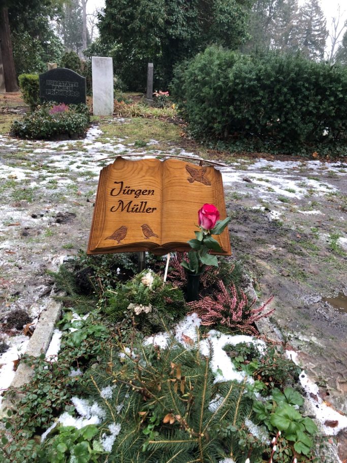 Grabstein als offenes Buch mit geschnitzten Vögeln und einer Blume